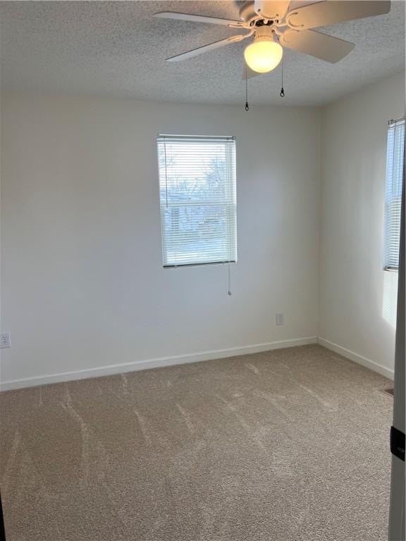 empty room with ceiling fan, a textured ceiling, and carpet