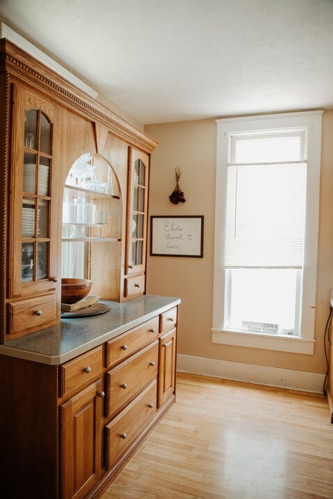 403 Maple St, Marshall, IL 62441 - kitchen with plenty of natural light, glass insert cabinets, light wood-style floors, and brown cabinets