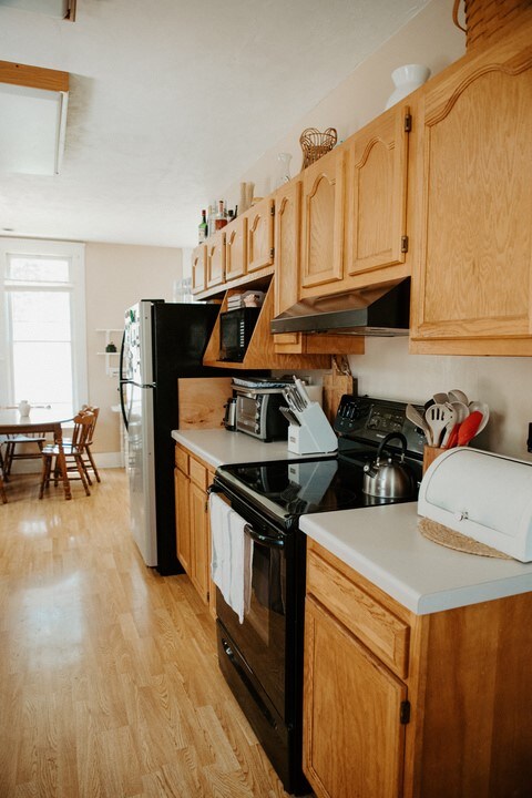403 Maple St, Marshall, IL 62441 - kitchen featuring black / electric stove, under cabinet range hood, light countertops, light wood-style floors, and freestanding refrigerator
