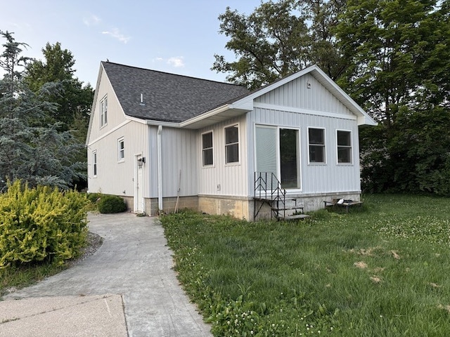 303 E Glenwood Ave, Olney, IL 62450 - view of front facade featuring entry steps, a shingled roof, concrete driveway, board and batten siding, and a front yard
