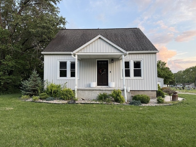 303 E Glenwood Ave, Olney, IL 62450 - view of front of home with a porch, a shingled roof, a front lawn, and board and batten siding