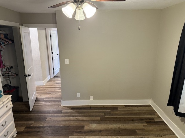 303 E Glenwood Ave, Olney, IL 62450 - unfurnished bedroom with dark wood-type flooring, ceiling fan, baseboards, and a closet
