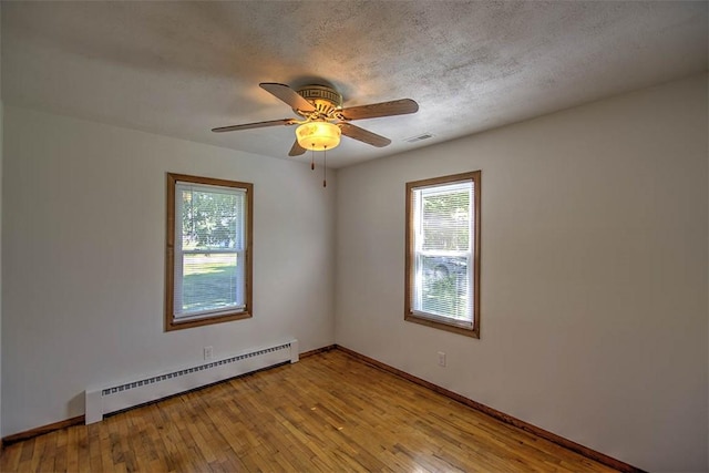 125 W Walnut St, Mt Zion, IL 62549 - empty room with baseboard heating, a ceiling fan, and hardwood / wood-style flooring