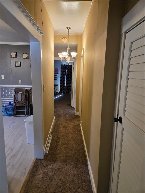 hall with a chandelier, carpet flooring, and baseboards