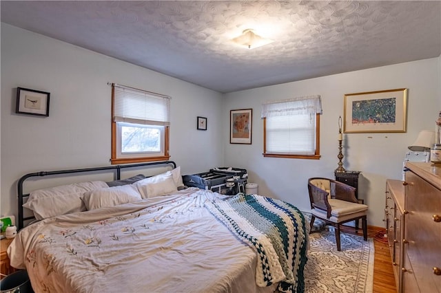 bedroom with a textured ceiling and light wood finished floors