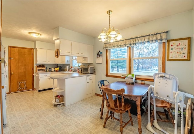 kitchen with a notable chandelier, white cabinets, light countertops, light floors, and decorative light fixtures