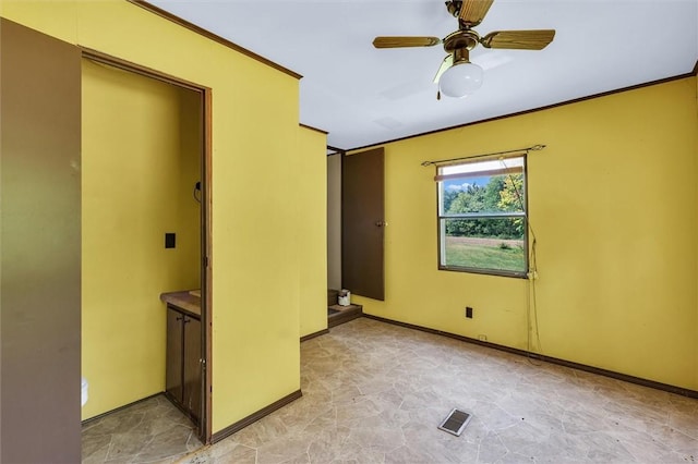 spare room with ceiling fan, ornamental molding, visible vents, and baseboards