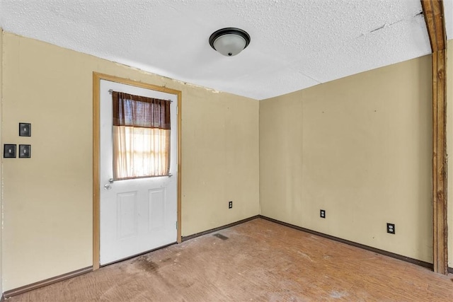 unfurnished room with a textured ceiling and baseboards