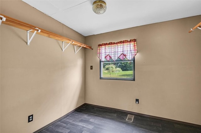 empty room featuring baseboards, visible vents, and dark wood-style flooring