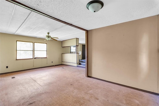 carpeted spare room with ceiling fan, a textured ceiling, visible vents, and baseboards