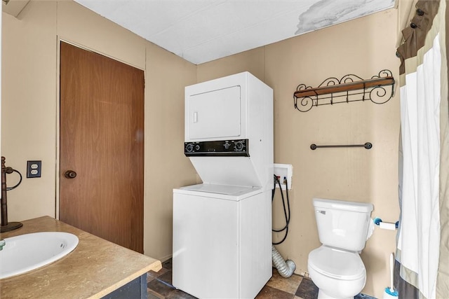 bathroom with stacked washer and dryer, vanity, and toilet