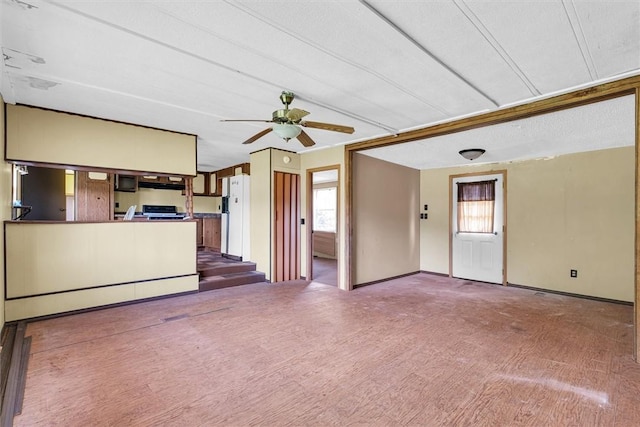 unfurnished living room with a healthy amount of sunlight, ceiling fan, and baseboards