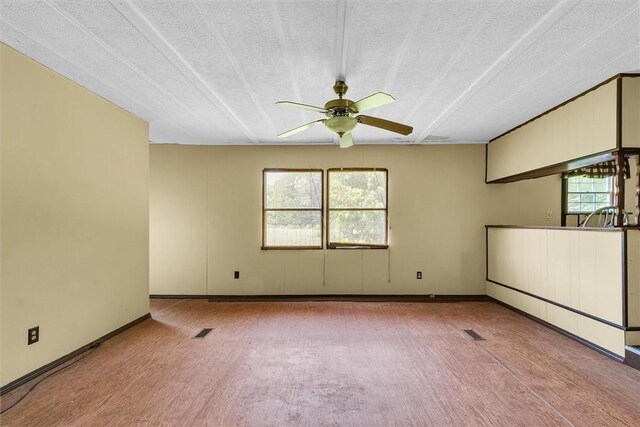 unfurnished room featuring a ceiling fan, visible vents, a healthy amount of sunlight, and a textured ceiling