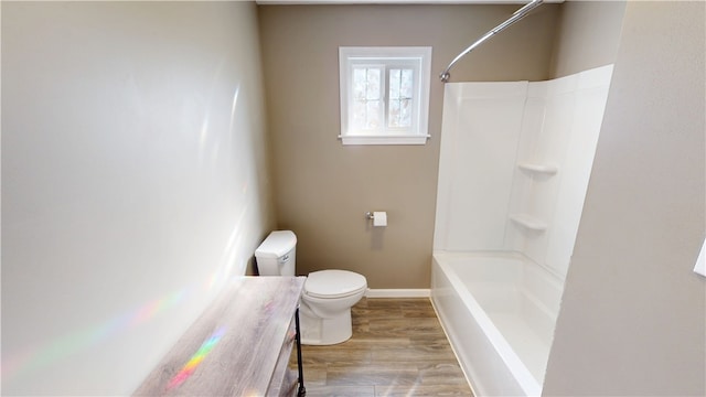 bathroom featuring baseboards, toilet, vanity, wood finished floors, and washtub / shower combination