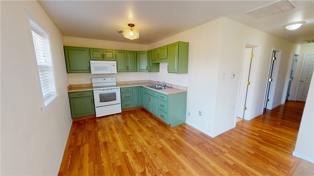 kitchen with a sink, white appliances, light wood-type flooring, and green cabinetry