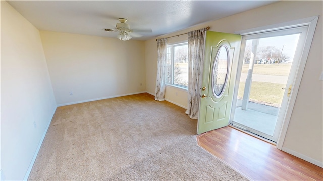 carpeted foyer featuring baseboards and ceiling fan