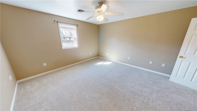 carpeted spare room with visible vents, baseboards, and ceiling fan