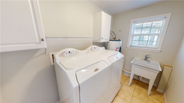 laundry area featuring light tile patterned flooring, cabinet space, water heater, a sink, and washing machine and dryer