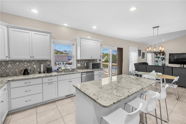 kitchen with white cabinets, a sink, stainless steel appliances, light tile patterned floors, and backsplash