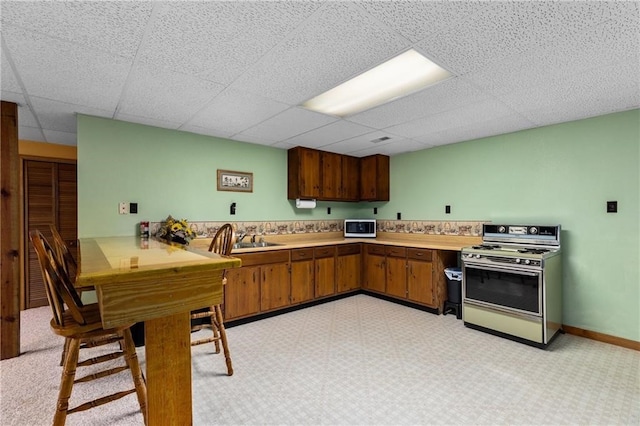 kitchen featuring sink, a paneled ceiling, and gas range oven