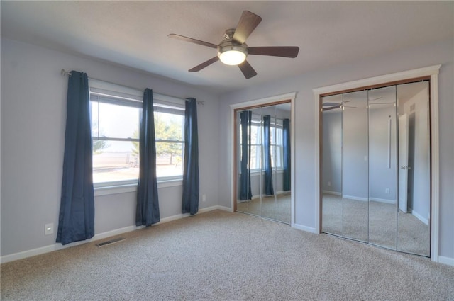 unfurnished bedroom with multiple closets, baseboards, visible vents, and carpet flooring