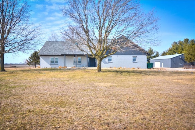 back of house featuring a yard and an outdoor structure