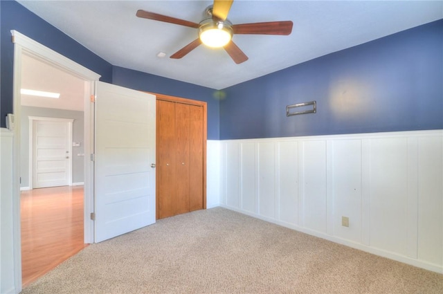 interior space with a ceiling fan and a wainscoted wall