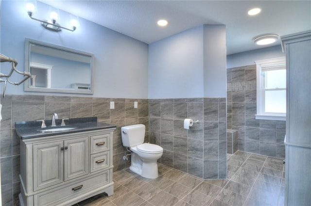 bathroom with toilet, tile patterned flooring, vanity, tile walls, and recessed lighting