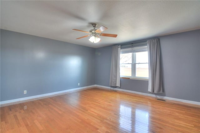 empty room featuring ceiling fan, light wood-type flooring, visible vents, and baseboards