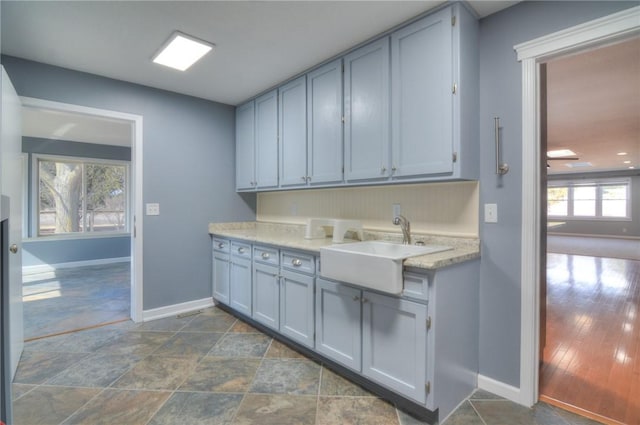 kitchen featuring baseboards, light countertops, and a sink