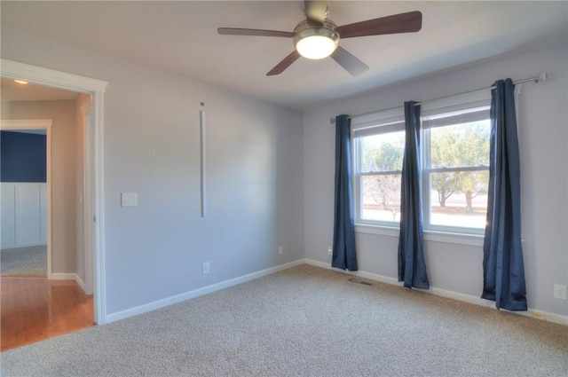 carpeted spare room with baseboards, visible vents, and a ceiling fan