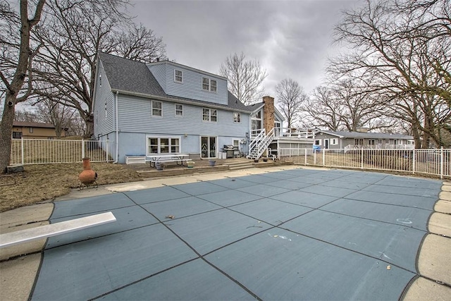 back of house featuring a wooden deck, a fenced backyard, and a fenced in pool