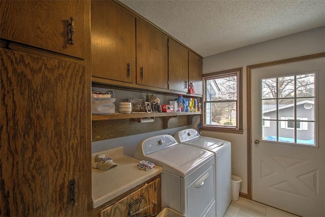 washroom featuring cabinet space, washer and clothes dryer, a textured ceiling, and light tile patterned floors