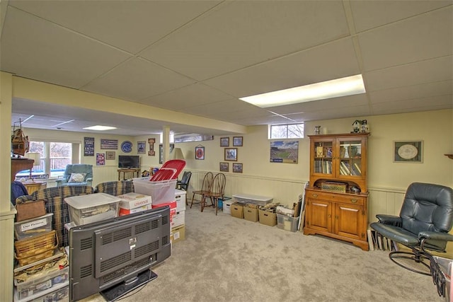 basement featuring a wainscoted wall, a paneled ceiling, and a wealth of natural light