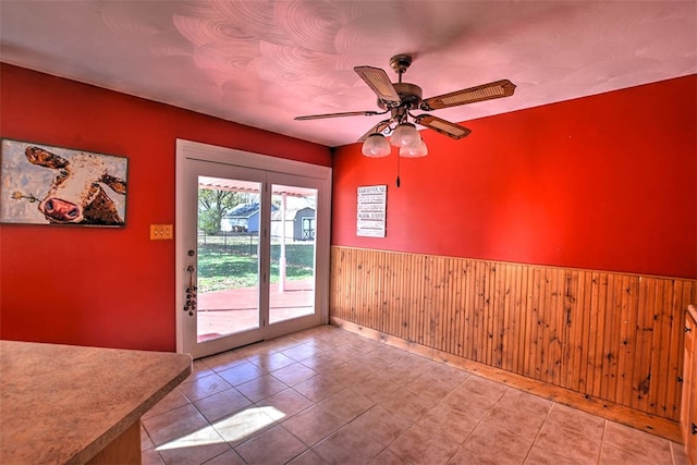 entryway with tile patterned floors, ceiling fan, and wood walls