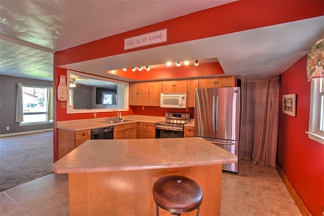 kitchen with sink, stainless steel appliances, kitchen peninsula, light carpet, and a breakfast bar