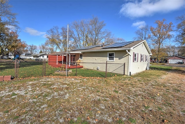 back of house featuring a lawn and solar panels