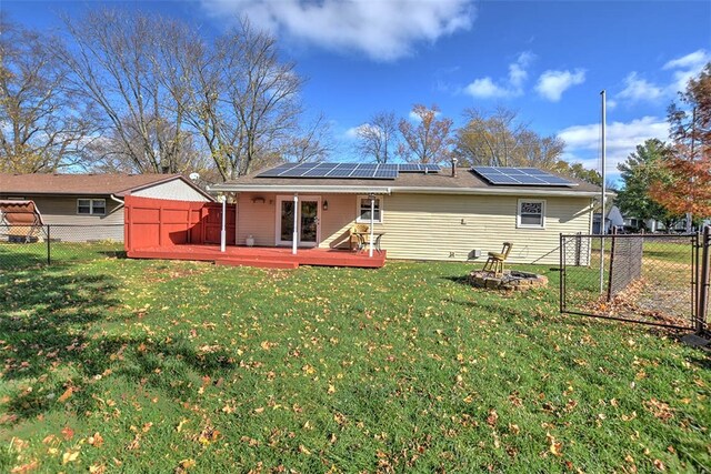 rear view of house featuring solar panels, a yard, a deck, and a storage shed