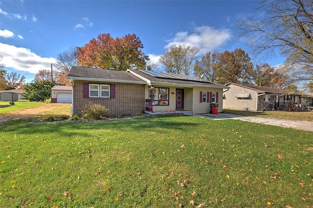 single story home with solar panels, a porch, an outdoor structure, and a front lawn