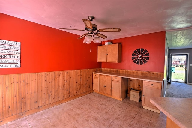 kitchen with built in desk, ceiling fan, and wooden walls