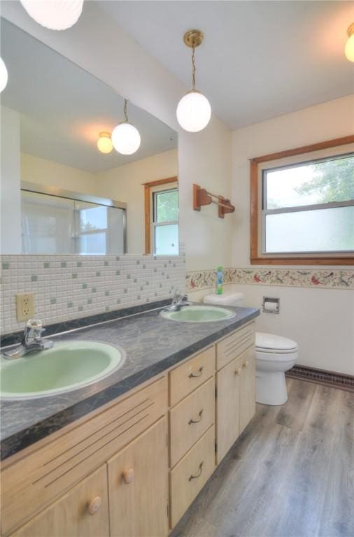 635 E N St, Warrensburg, IL 62573 - bathroom featuring double vanity, an enclosed shower, toilet, wood finished floors, and a baseboard radiator