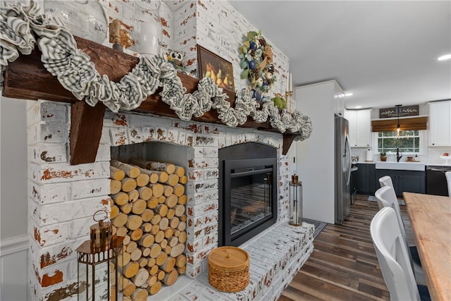 living room featuring a fireplace, dark wood-type flooring, and sink