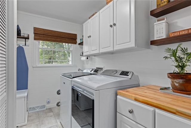 washroom featuring separate washer and dryer, light tile patterned floors, cabinets, and ornamental molding