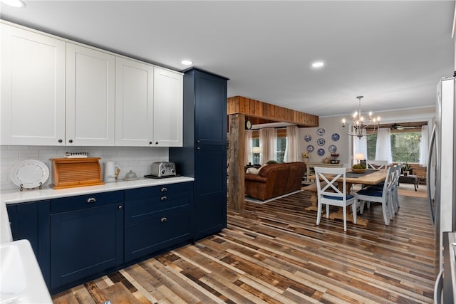 kitchen featuring blue cabinetry, dark hardwood / wood-style flooring, a chandelier, decorative light fixtures, and decorative backsplash