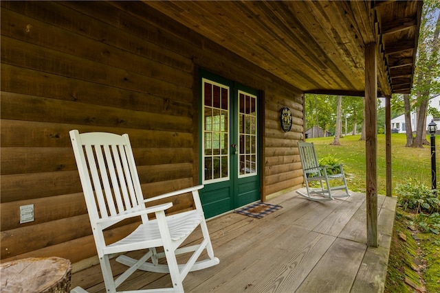 wooden terrace featuring covered porch and a yard