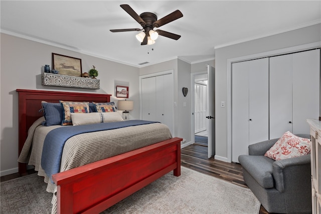 bedroom with dark hardwood / wood-style floors, ceiling fan, ornamental molding, and multiple closets