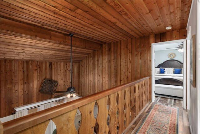 hall featuring wooden walls, dark wood-type flooring, wood ceiling, and vaulted ceiling