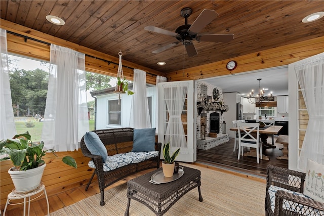 sunroom featuring a fireplace, wooden ceiling, and ceiling fan with notable chandelier