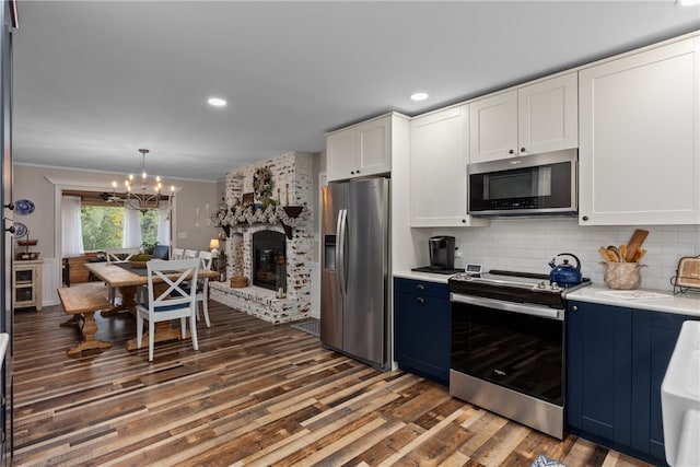 kitchen with a fireplace, stainless steel appliances, white cabinets, and blue cabinetry