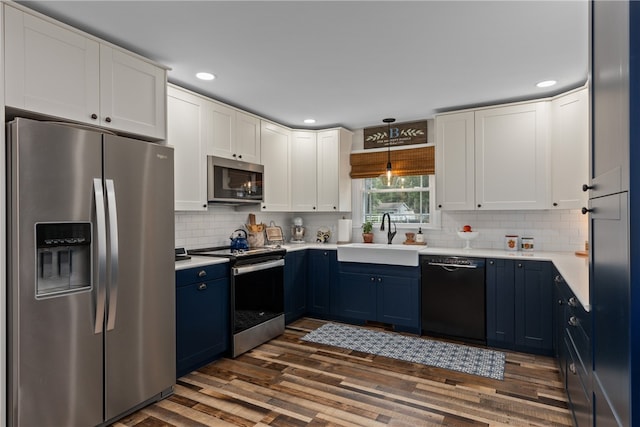 kitchen with blue cabinetry, sink, dark hardwood / wood-style floors, decorative light fixtures, and appliances with stainless steel finishes